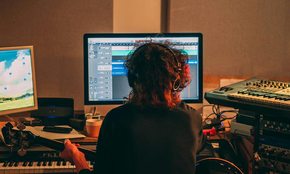 Productor trabajando en su estudio para desarrollar un estilo musical propio y original